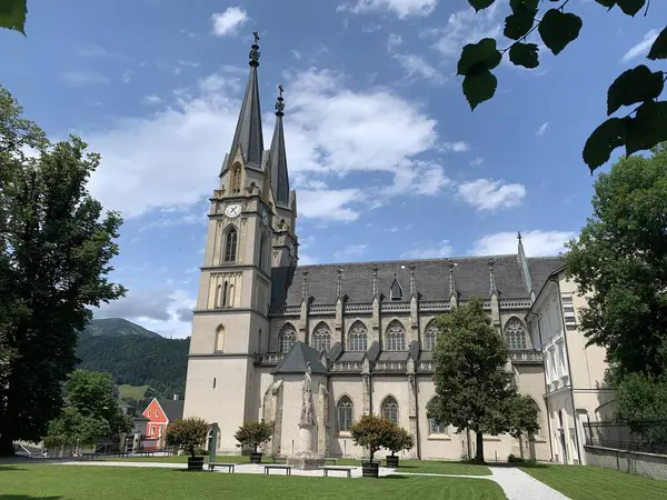 stock image Admont, Styria, Austria, July 13, 2024: View of Admont Abbey Church, neo-gothic architecture. Framed by leaves. Benedictine Monastery since 1074. Located at the foothills of Nationalpark Gesaeuse.