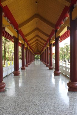Kaohsiung, Tayvan, 23 Mart 2024: Güzel kırmızı, sarı renkli, ahşap, sütunlu bir çatı koridoru. Dışarıda, Kaohsiung 'daki Fo Guang Shan Manastırı' nda. Dikey görüntü. Sonsuz düz bir geçit.