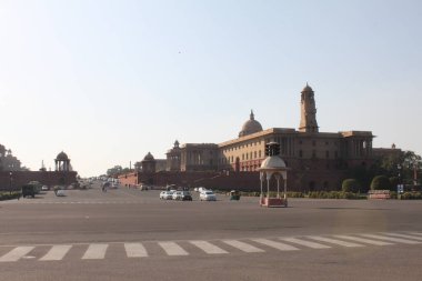 Yeni Delhi, Hindistan, 7 Mart 2019: Hindistan Parlamentosu 'nun Yeni Delhi, Hindistan' daki Streetview 'i. Baharda güneşli bir gün. Trafiğin kesiştiği büyük bir yer. Politik hükümet binaları. Önde koruyucu yol.