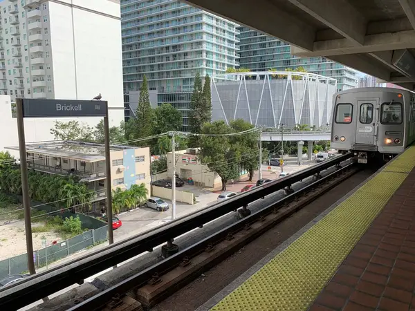 Miami, FL, ABD, 11 Şubat 2020: Brickell istasyonu Miami, Florida 'da bulunan bir metro istasyonudur. Tren geliyor. Arka planda modern binaların ve ağaçların görüntüsü.