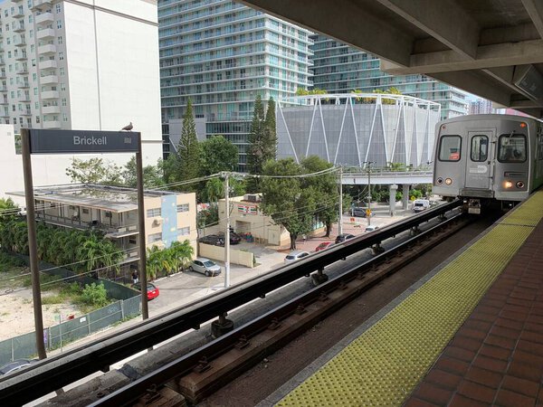 Майами, штат Флорида, США, 11 февраля 2020 года: Станция Брикелл - это станция быстрого пересадки металла в Майами, штат Флорида, в финансовом районе. Поезд прибывает. Вид на современные здания и деревья на заднем плане.
