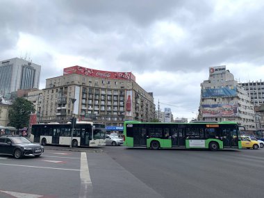 Bükreş, Romanya, 3 Temmuz 2024: Victoriei Meydanı 'nda trafik. Bükreş şehir merkezinde yoğun bir kavşak var. Otobüsler, arabalar. Coca Cola ve McDonalds için büyük format reklamları olan eski konut binaları.