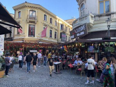 Bükreş, Romanya, 3 Temmuz 2024: Lipscani bölgesinde sokak köşesi. Lipscani bölgesindeki oturma alanının dışında kalabalık olan insanlar, eski Bükreş 'teki restoran ve barlarda sıcak hava koşulları bekliyorlar..