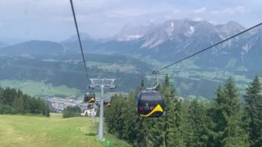 Schladming, Avusturya 12 Temmuz 2024: Dachstein Massif 'in panoramik manzarası, doğu Alpler, vadideki Schladming köyü (Ennstal). Planai Schladming teleferiği, yazın kayak pistleri..