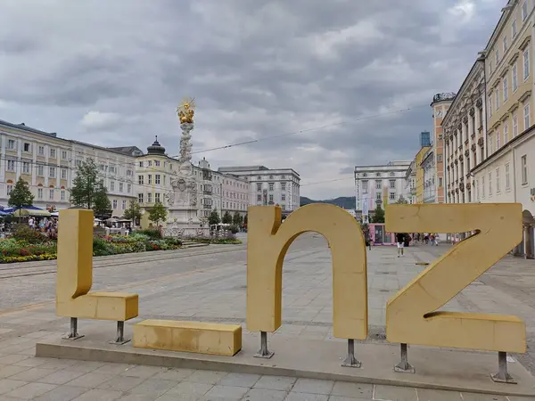 Linz, Avusturya, 25 Ağustos 2024: Arka planda büyük harflerle yazılan büyük harflerin turistik cazibesi ve tarihi binalar. Şehir merkezi, ana meydan Linz, Yukarı Avusturya.