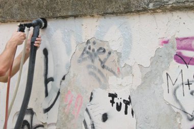 Pecs, Macaristan, 8 Ağustos 2024: Pecs şehir merkezindeki Bishops Sarayı 'nın duvarında fırçayla etkili grafiti temizleme. Şehir, olumsuz dışsallığın yükünü kaldırarak alır..