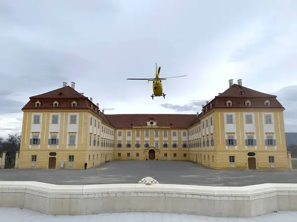 stock image Schlosshof, Austria, March 1, 2020: Air rescue helicopter takes off in front of baroque estate Schloss Hof, Lower Austria. Emergency medical trauma helicopter operated by Austrian Touring Club (OEAMTC) in courtyard of medival castle.