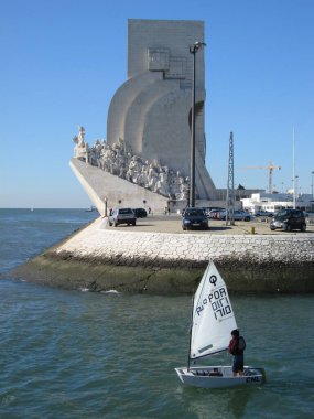 Lisbon, Portugal  January 27, 2007: Boy sailing in front of Monument of Discoveries (Padro dos Descobrimentos) on river Tejo or Tagus. Monument celebrates Portuguese Age of Discovery or Exploration. Vertical image. clipart