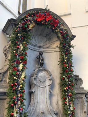 Brüksel, Belçika - 15 Ocak 2024: Manneken Pi Noel süslemesiyle çerçevelenmiştir. Manneken Pi (Hollandaca 