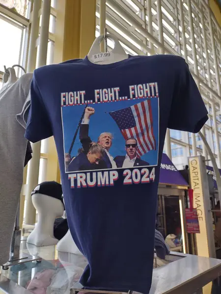 Arlington, VA, ABD - 19 Eylül 2024: Tişört Donald Trump 'ı suikast girişiminden sonra gösteriyor. Kelimelerle üç kez kavga. Ronald Reagan Washington Ulusal Havalimanı 'ndaki hediyelik eşya dükkanında satılık..