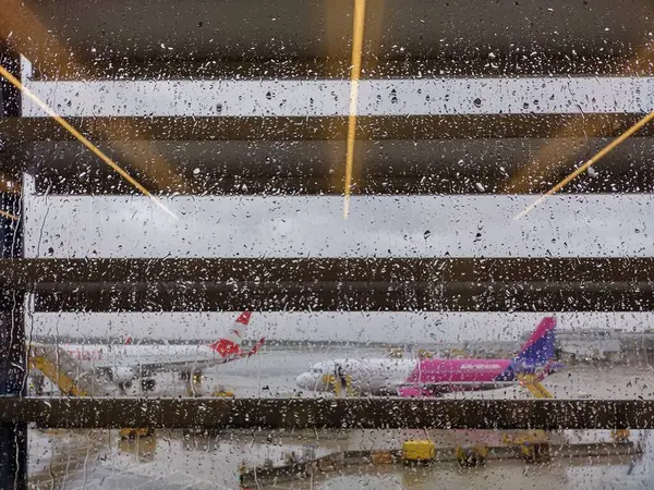 Schwechat, Avusturya, 15 Eylül 2024: Avusturya Havayolları ve Wizz Hava Yolları terminallerindeki yağmur damlalarıyla dolu ıslak pencereden bakın. Viyana Uluslararası Havaalanı. Yağmurlu bir gün. Şiddetli fırtına ve kötü hava koşulları.