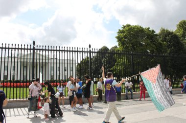 Washington DC, ABD, 16 Eylül 2024: Filistin bayrağı taşıyan erkek protestocu orta parmağını Amerika Başkanı 'nın ikametgahı Beyaz Saray' a doğru gösteren soykırıma son verdiğini söylüyor.