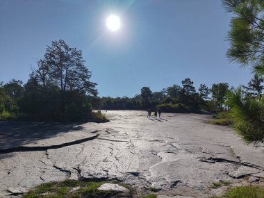 Stone Mountain, Georgia, ABD 20 Eylül 2024: Güneşli bir sonbaharın ilk günlerinde Stone Mountain Park 'ta Aile Yürüyen Dağ Yolu. Pürüzsüz granit arazi. Parlak güneş ışığı, arka plan.