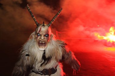 Gaenserndorf, Avusturya - 23 Kasım 2024: Geceleri Avusturya 'da Krampuslauf veya Perchtenlauf. Boynuzlu antropomorfik figürler. Orta ve Doğu Alp folklorik geleneği. Kılıç kostümü. Ateş, arka planda duman.