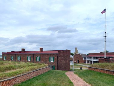 Baltimore, Maryland, USA - September 17, 2024: Flag pole with Star-Spangled Banner between enlisted men's barracks, powder magazine, commanding officer's quarters and guardhouse at parade ground of Fort McHenry National Monument and Historic Shrine. clipart