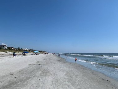 Hilton Head Adası, SC, ABD 24 Eylül 2024: Güney Carolina 'daki Hilton Head Adası' ndaki Coligny Beach Park 'ta güneşli bir günde güzel bir plaj. İnsanlar rıhtımda yürüyor, şemsiye kuruyorlar..