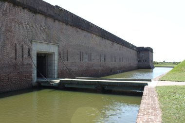 Savannah, Gürcistan, ABD - 23 Eylül 2024: Asma köprü, portcullis evi, granit kaplama, su dolu hendek, embriyolar ve Fort Pulaski Ulusal Anıtı 'nın güneybatı kalesinin geçit duvarı.