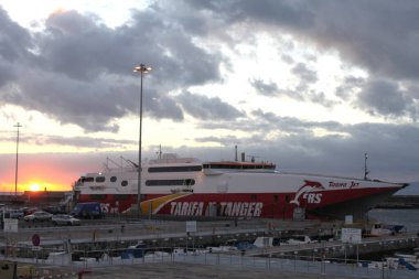 Tarifa, Andalusia, Spain  November 8, 2010: HSC Tarifa Jet operated by FRS Iberia moored at Tarifa port. Ferry crossing strait of Gibraltar into Africa. Service between Continental Europe and Morocco. Morning mood at sunrise with clouds. clipart