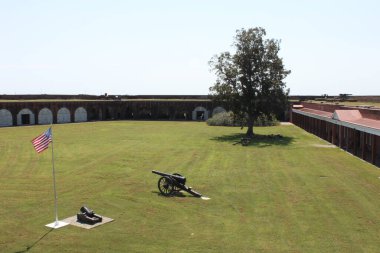 Savannah, Georgia, USA - September 23, 2024: Parade ground, parrott with mortar next to flag pole with Star-Spangled Banner, Terreplein with cannons within massive brick walls of Fort Pulaski National Monument. clipart