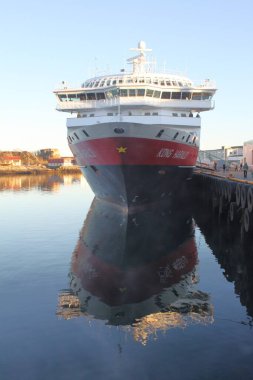 Svolvaer, Vagan, Nordland, Norveç - 17 Nisan 2019: Hurtigruten gemisi MS Kong Harald baharda gün batımında Svolvaer rıhtımına demir attı. Lofoten Adaları 'ndaki Norveç limanındaki geminin dikey görüntüsü.