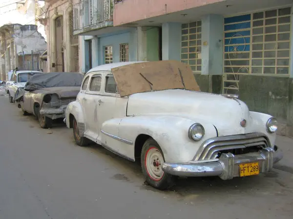 Centro Habana, Havana, Küba - 14 Mart 2009: Havana Mahallesi 'nde park halindeki klasik arabaların bulunduğu tipik sokak sahnesi. Kırsal beyaz Oldsmobile 'in ön camında karton  