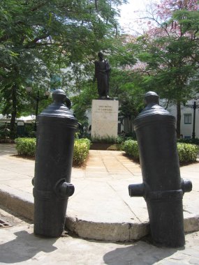 Centro Habana, Havana, Cuba - March 14, 2009: Statue of Simon Bolivar on Pedestal in downtown Havana, square confined by old canon barrels rammed upside down into ground. Sunny day. Vertical image clipart