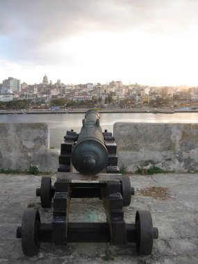 Eski Havana, Havana, Küba - 15 Mart 2009: Havana limanının girişini koruyan Castillo del Morro Kalesi. Tahta arabadaki top, devasa duvarlardan merlonlara nişan alıyor. Baharda gün batımı. Dikey resim.