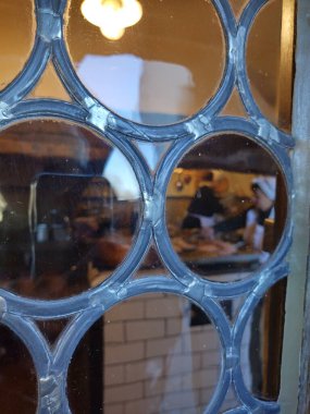 Regensburg, Bavaria, Germany, November 30, 2024: View inside kitchen of historic Wurstkche (sausage kitchen) through antique glass window. Vertical clipart