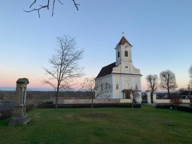 Rabensburg, Gnserndorf, Aşağı Avusturya - 25 Kasım 2022: St. Helena Kilisesi, soğuk sonbahar akşamı, gün batımından önce bulutsuz mavi gökyüzü. Avusturya ile Slovakya arasında sel baskınları var.