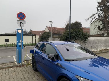 Ganserndorf, Aşağı Avusturya - 06 Ocak 2025: Soğuk bir kış günü şarj istasyonunda park halindeki elektrikli araba.