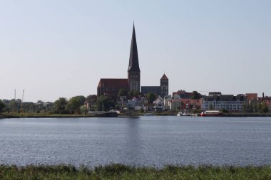 Rostock, Mecklenburg-Batı Pomerania, Almanya - 23 Ağustos 2009: Hanseatic şehri Rostock 'un St. Nicholas Kilisesi ve St. Peter Kilisesi ile ufuk çizgisi üzerinde Unterwarnow (Warnow Nehri' nin kıyısı).