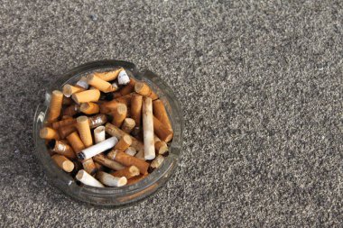 Ashtray full of different cigarette butts and filters, yellow and brown from Nicotine. Put out your cigarette and quit smoking now! clipart