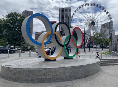 Atlanta, GA, ABD - 28 Eylül 2024: Atlanta şehir merkezindeki Centennial Olimpiyat Parkı 'nda Olimpiyat Halkaları, SkyView Atlanta, arka planda taşınabilir dönme dolap. Bulutlu bir günde gezmek.