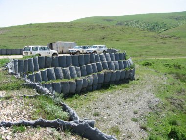 Harilaq, Priştine, Kosova - 20 Mayıs 2006: Atış poligonunda park edilmiş UNMIK Toyota 4Runner araçları filosu. Hesco konteynırları taş ve çakıl katmanlarının ağırlığı altında yavaşça çöker..
