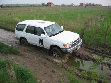 Priştine, Kosova - 28 Nisan 2006: UNMIK Toyota 4Runner savaş sonrası Prishtina yakınlarındaki sel basmış bir toprak yolda su ve çamura bulaştı.