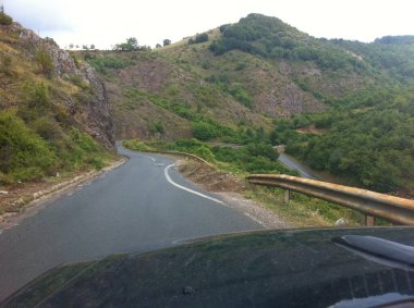 Kosovo - August 05, 2011: Interesting paint of edge line strictly following road shoulder of a steep curved mountain road. Painters totally failed. clipart