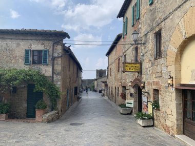 Monteriggioni, Siena, Toscana, Italia - 27 Eylül 2021: Piazza Roma 'dan Monteriggioni şehir duvarının kuzey kapısına kadar olan orta çağ kasabasının ana caddesi üzerinde Porta Fiorentina (di San Giovanni).