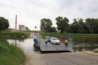 Angern an der March, Lower Austria, Austria - August 4, 2024: Small car ferry crossing river Morawa between Angern an der March, Lower Austria and Zahorska Ves, Slovakia. Heading west to Austria. River forms the border. clipart