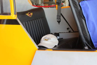 Marathon, FL, US - February 14, 2020: Cap with logo and lettering found on passenger seat of American Legend Classic Cub J3 parked in EAA Air museum Chapter 1241 at Florida Keys Marathon Airport. clipart