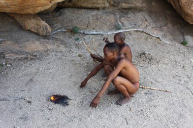 Omandumba, Namibya - 15 Mart 2018: San People 'ın iki köylüsü binlerce yıl önce atalarının yaptığı gibi ateş yakmaya devam ediyor..