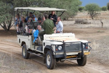 Okapuka Çiftliği, Namibya - 19 Mart 2018: Tipik bir safari aracında sürücü ve rehberli turistler.