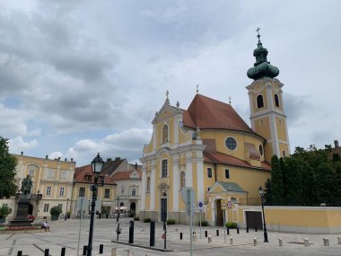 Gyor, Macaristan, 4 Ağustos 2024: Gyor 'daki Karmelite Kilisesi (Karmalita templomu) 1721 ile 1725 yılları arasında erken dönem İtalyan Barok tarzında inşa edilmiştir. Macar tiyatro sanatçısı Kisfaludy Karoly 'nin heykeliyle kare.
