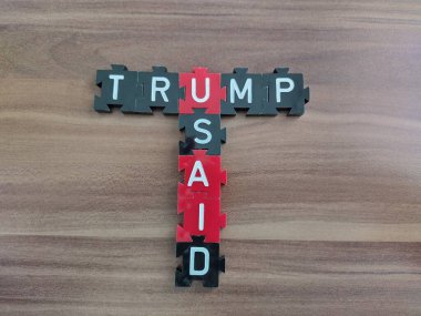 Viyana, Avusturya 8 Şubat 2025: USAID sözcüğüne ve Başkan Donald Trump 'ın soyadıyla kırmızı ve siyah simgeler üzerine kırmızı kart oyunu harfleriyle çapraz bulmaca şeklinde yazılmış.. 