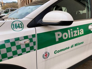 Milan, Lombardy, İtalya - 14 Şubat 2025 İtalyan polis devriye arabasının yanında. Etiketli Polizia (polis) ve Milano Komünü 'nün Milano şehri arması, şeritleri yansıtıyor.