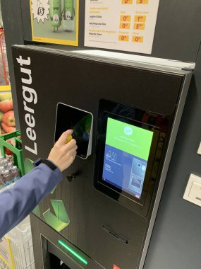 Ganserndorf, Avusturya 7 Mart 2025: Kadın elinin arka depozito almak için şişeyi ters çevirme makinesine koymasının ayrıntıları. Boşların dönüşü. Avusturya depozito iade sistemini 2025 yılında başlattı.