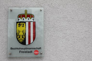 Freistadt, Yukarı Avusturya - 11 Mart 2025: Oberoesterreich arması ile Bezirkshauptmannschaft 'ı (Freistadt bölge otoritesi) gösteren cam panel. Kırmızı yuvarlak Alman etiketi: Yukarı Avusturya.