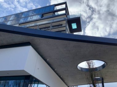 Freistadt, Avusturya - 11 Mart 2025: Genişletilmiş düz çatılı ve yuvarlak biçimli Hotel Freigold, cam dipli gökyüzü havuzlu modern bir şehir spa oteli. İlkbaharda bulutlarla güneşli bir gün Muhlviertel.