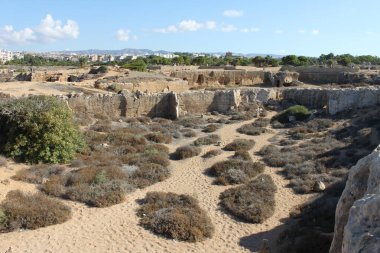 Paphos, Kıbrıs - 02 Ekim 2018: Kings 'in Mezarları üzerine panoramik manzara, sert kayalardan oyulmuş ve arka planda modern Paphos kentinin ufuk çizgisi ile çevrelenmiş manzara.