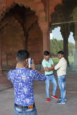 Yeni Delhi, Hindistan - 7 Mart 2019: Hintli gençler Diwan-i-Aam 'da poz veriyorlar. Arkadaşları akıllı telefonuyla fotoğraf çekiyor..