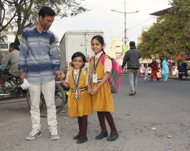 Jaipur, Rajasthan, Hindistan - 08 Mart 2019: Şehir merkezinde yoğun vatandaşlarla sokak sahnesi. Gururlu baba okuldan sonra kızlarını eve götürür..